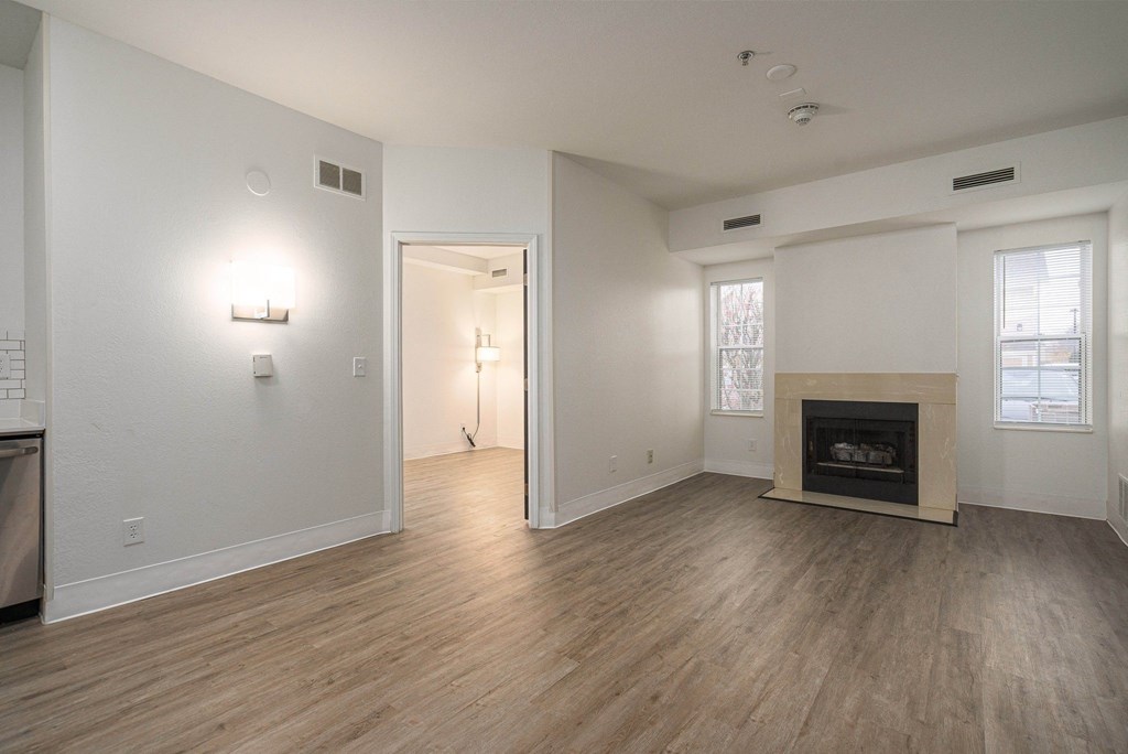 an empty living room with a fireplace and wood flooring